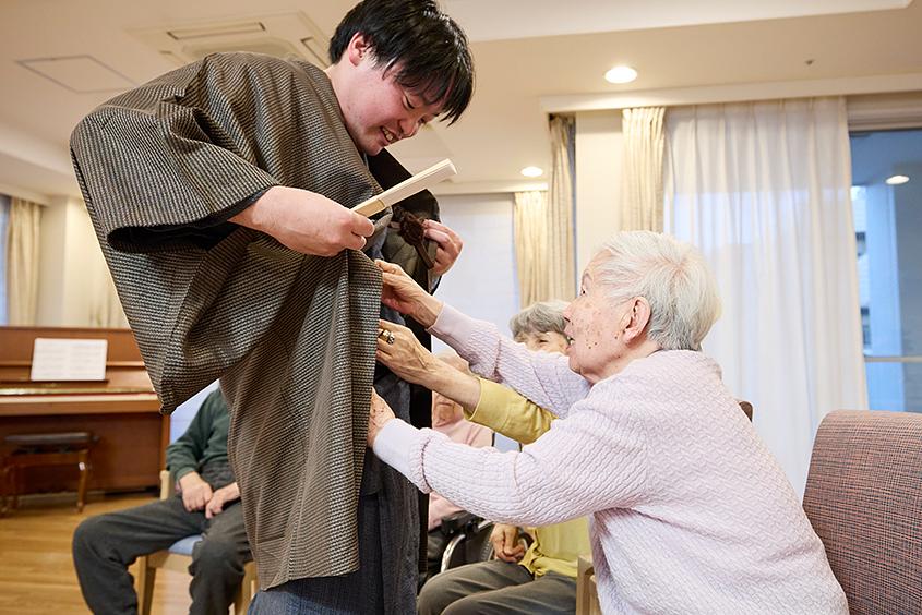 「落語の会」が始まる前、高座に上がるスタッフの着物と帯を直してくださるご入居者様のご様子。